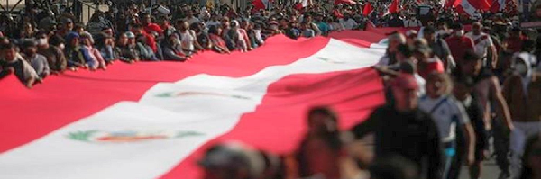 Demonstrant*innen tragen eine riesige peruanische Flagge. Quelle: CNDDHH/Servindi