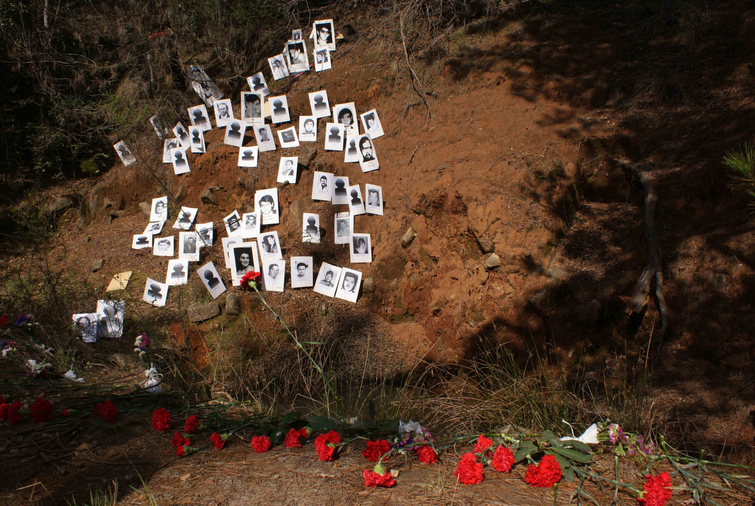 Blumen und Fotos von Verschwundenen an einem Massengrab in der Ex Colonia Dignidad