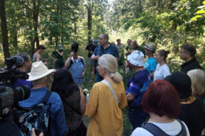 Mitglieder der BI Grünheide erklären auf Waldweg vor der Presse und Interessierten den aktuellen Stand der Planung.