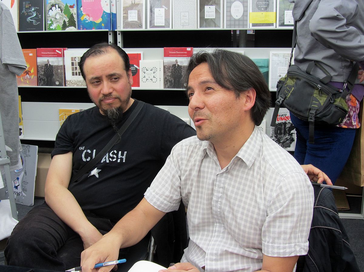 Autor Carlos Reyes und Zeichner Rodrigo Elgueta bei der Internationalen Buchmesse in Santiago de Chile, 2015.
Foto: Rodrigo Fernández via wikimedia
CC BY-SA 4.0 Deed