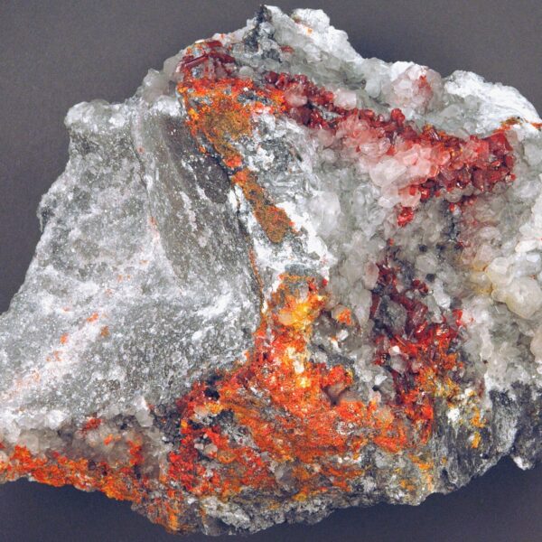 Realgar (rot) und Pararealgar (orange und gelb) sowie Calcitkristalle auf Marmor 
Foto: James St. John via wikimedia
CC BY 2.0